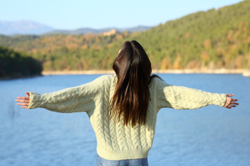 Bak view of a woman outstretching arms in nature