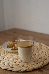 Dalgona coffee in a glass on a wooden table, with croissants.