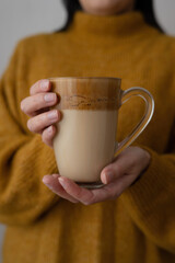 In the hands of a young woman, Dalgona coffee.