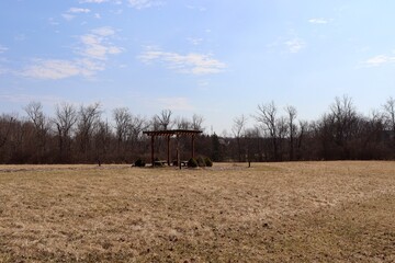 The wood shelter park bench in the field on a sunny day.