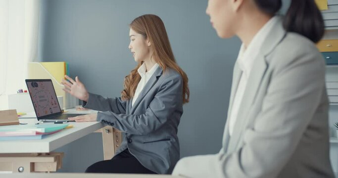 Group of young asia creative team discuss project compare point in paperwork and laptop on table working and communicating together on office desk at workplace. Partner cooperation, coworker teamwork.