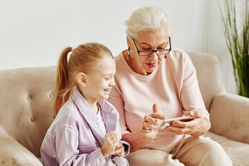 Minimal portrait of senior grandmother using smartphone with little girl smiling happily