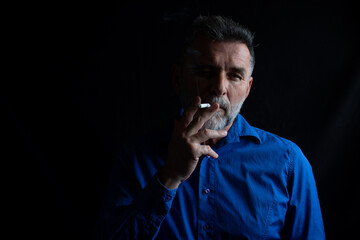 Portrait of handsome stylish mature man in smoking at looking at camera
