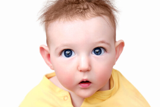 Surprised infant baby boy with big eyes on a white background, isolated. Portrait of a frightened child with a messy hairstyle