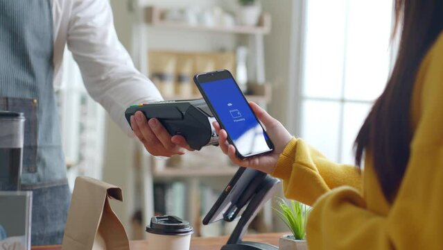 Customer using smartphone for NFC payment at cafe restaurant, cashless, contactless technology and money transfer concept