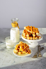 Croffle or waffle with croissant. Breakfast arrangement featuring crispy waffles, a milk bottle with cork, and a filled glass.