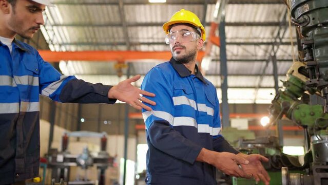 Angry engineer boss scolding young engineers for their mistake standing in the CNC manufacturing factory. Negative boss yelling employee during work. Man standing and feeling bad. Industrial concept 