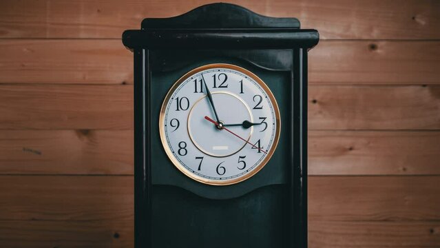 Timelapse of vintage clock with full turn of time hands at 3 am or pm on wooden background. Old Retro wall clock with white circular dial. Old-fashioned antique clock. Arrows second, minute, and hour