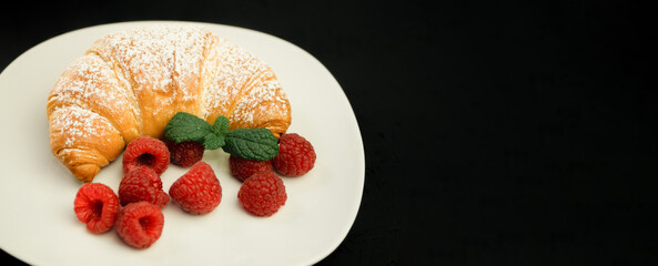 Appetizing crispy croissant and fresh raspberries on a white plate