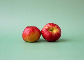 Two red apples on a green background aesthetics of fruit