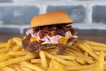 Smash burger with coleslaw sauce, bacon on top of a potato bed