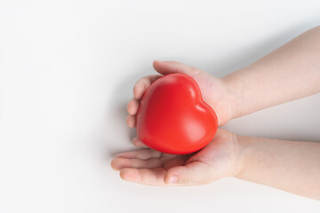 Childrens hands holding a red heart