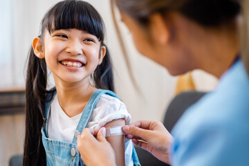 Childhood vaccination. Asian young woman doctor vaccinating little girl at home. Vaccine for...