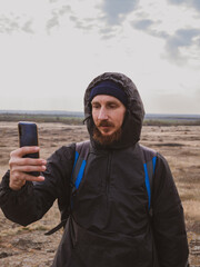 Bearded traveler hiker photographer man with smartphone backpack walking climbing mountain summit taking picture of scenic landscape cloudy sky. Active Lifestyle Solo Travel Hiking Backpacking extreme