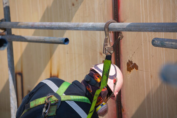 Male worker wearing safety first harness and safety lone working at high beam place on top roof