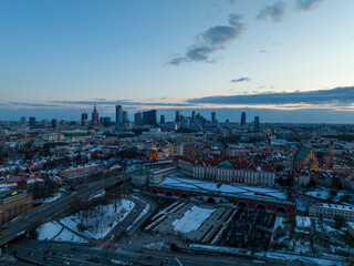 Obraz na płótnie Canvas Widok na zamek królewki i stare miasto w Warszawie z drona, w tle wieżowce, zaśnieżone dachy, zachód słońca