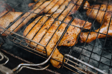Chicken thighs are fried on the grill in a barbecue. Picnic in nature.