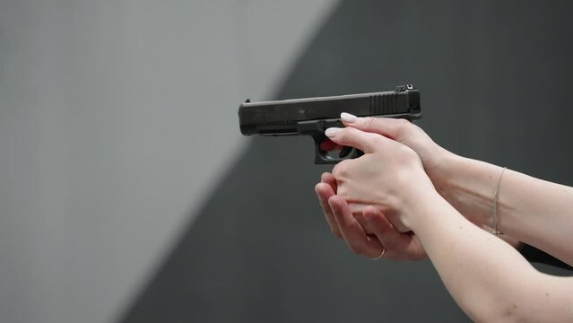 A woman practice gun shooting, women's hands with a pistol are pulled by a man's hand, shooting gallery, 4k slow motion