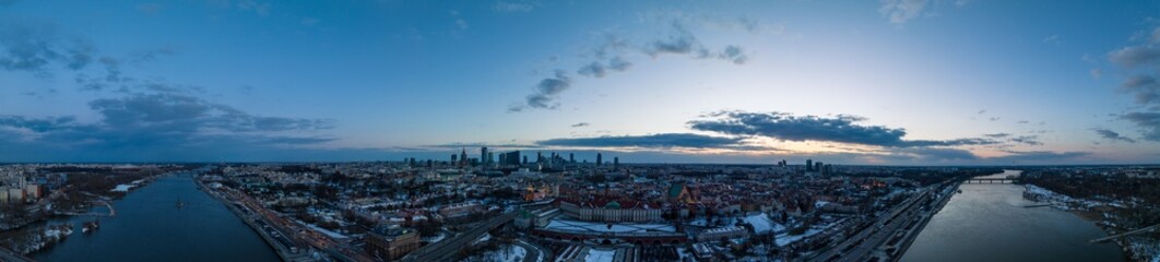 Fototapeta Panorama, Widok na zamek królewki i stare miasto w Warszawie z drona, w tle wieżowce, zaśnieżone dachy, zachód słońca obraz