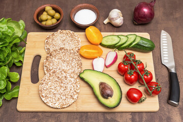 Cooking vegan vegetarian sandwiches with different vegetables and toasts of whole grain bread on kitchen. Healthy diet food concept