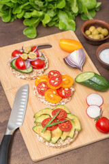 Toasts with vegetables, tomato, avocado, cucumber on whole grain bread on wooden background. Healthy breakfast, plant based, vegan, vegetarian food