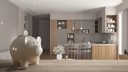 Wooden table top or shelf with white piggy bank with coins, modern bright kitchen with dining table, expensive home interior design, renovation restructuring concept architecture