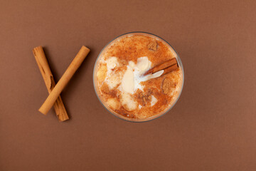 Salep or Sahlep in glass on brown background, top view. Salep - Turkish traditional drink with cinnamon. Selective focus, copy space