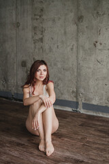 Naklejka premium Portrait of young pretty caucasian woman with natural makeup wearing light body in minimalistic loft interior. Youth, freshness, beauty, happiness, emotions concept.