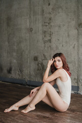 Naklejka premium Portrait of young pretty caucasian woman with natural makeup wearing light body in minimalistic loft interior. Youth, freshness, beauty, happiness, emotions concept.