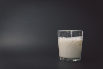 Glass filled to the top with delicious fresh milk on a black background leaving copy space. Image of a delicious glass of milk prepared to consume at any time of the day.