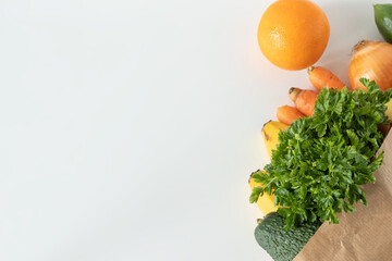 Paper bag with fresh plant-based groceries: vegetables and fruits isolated on white background with...