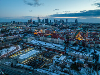 Widok na zamek królewki i stare miasto w Warszawie z drona, w tle wieżowce, zaśnieżone dachy, zachód słońca