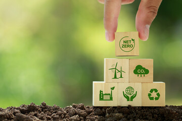Net zero and carbon neutral concept. Hand puts wooden cubes with netzero icons - renewable energy,...