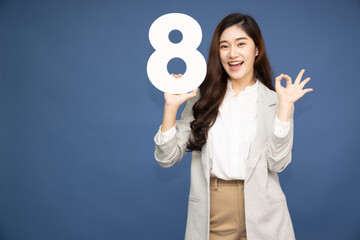 Young Asian business woman showing number 8 or eight isolated on deep blue background
