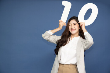 Young Asian business woman showing number 10 or ten isolated on deep blue background