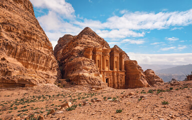 Ad Deir - Monastery - ruins carved in rocky wall at Petra Jordan, mountainous terrain with blue sky background