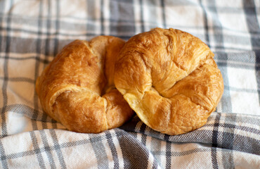 two baked croissants on a plaid tablecloth