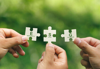 ESG concept of environmental, social, and governance.Hand of people holding a piece of jigsaw...