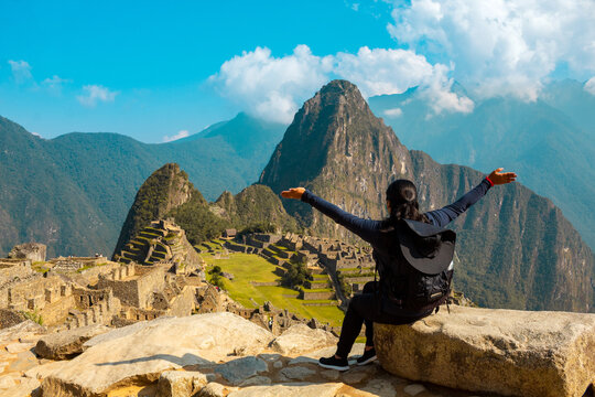 Una mujer turista con una mochila contemplando el asombroso paisaje de Machu Picchu con los brazos abiertos. Sitio arqueológico, Patrimonio de la Humanidad de la UNESCO, concepto de turismo