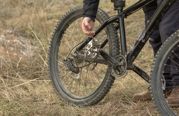 Fototapeta premium a young cyclist is sitting on the grass and repairing a loose chain on a mountain bike..