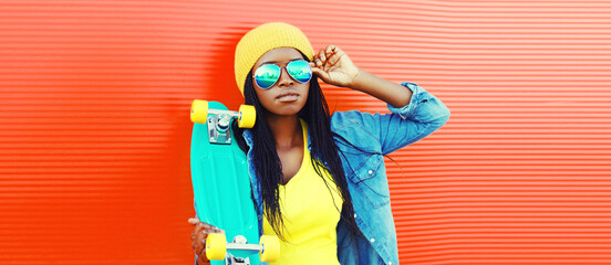 Portrait of young african woman with skateboard wearing sunglasses, hat in casual on vivid background, blank copy space for advertising text - obrazy, fototapety, plakaty