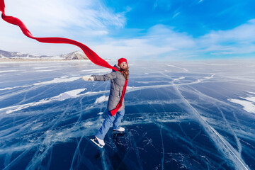 Happy woman tourist on ice skates and with long red scarf on frozen lake Baikal. Concept winter tourism freedom