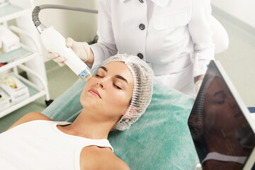 Doctor and woman client during radiofrequency lifting treatment in a medical aesthetic clinic
