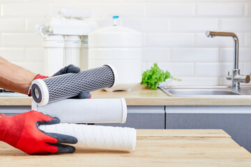 Hands holding a filter cartridge of domestic drink water treatment systems at kitchen background....