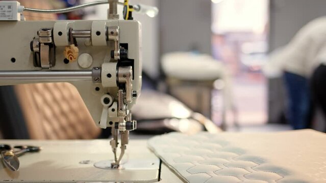 step sewing machine. close view of mechanism of non-working sewing machine in bright, airy atelier. Under needle lies cowhide on which pattern is embroidered.