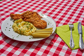 Deep fried chicken escalope or schnitzel with mashed potatoes and pickled cucumbers. Served on...