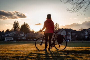 Adventurous Woman Standing with a bicycle at a Park in Modery City Suburbs. - obrazy, fototapety, plakaty
