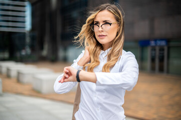 Confident young female manager outdoor checking the time on her watch
