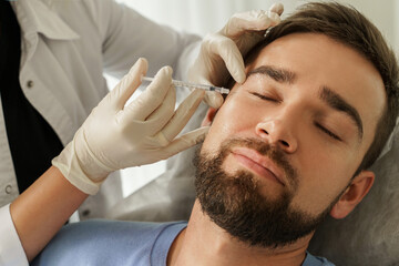 Fototapeta premium Female doctor and male client during filler injections in clinic