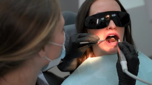 Woman dentist at work. Dental treatment in a modern dental clinic. Female patient in sunglasses